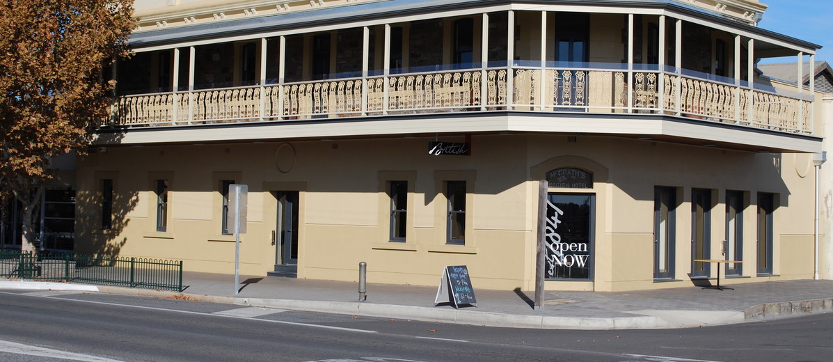 Image: A cream-coloured two-storey building with upstairs verandah. A sign over the front door reads ‘McGrath’s British Hotel’