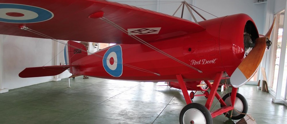 Image: A bright red First World War-era monoplane on static exhibit in a museum