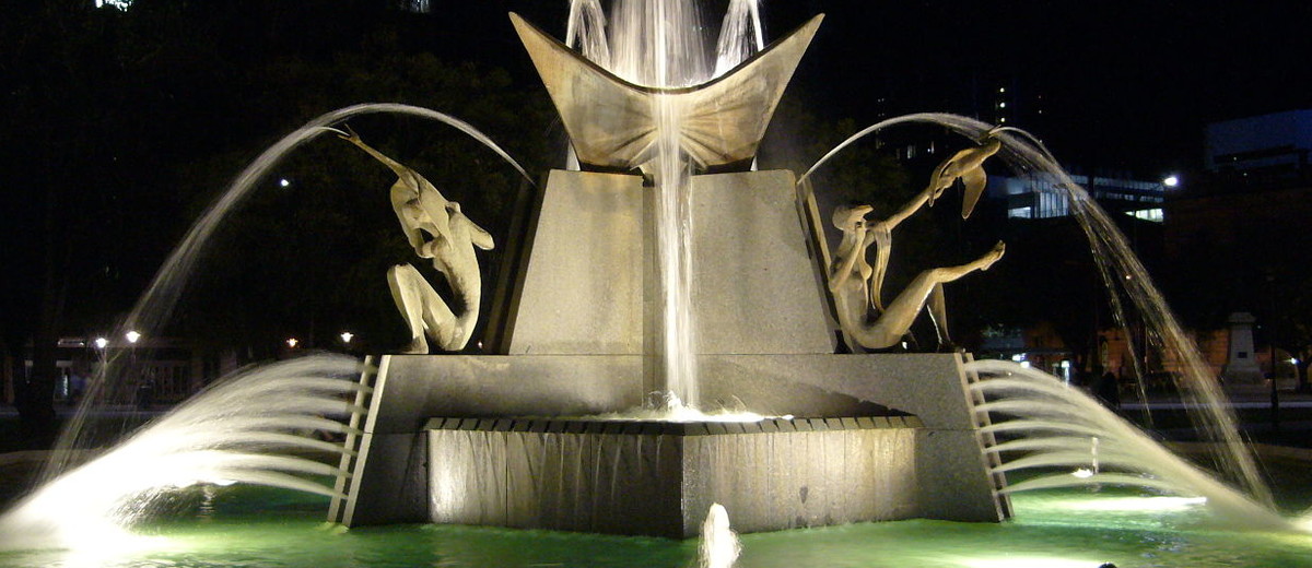 Image: large fountain featuring human figures and birds lit up at night