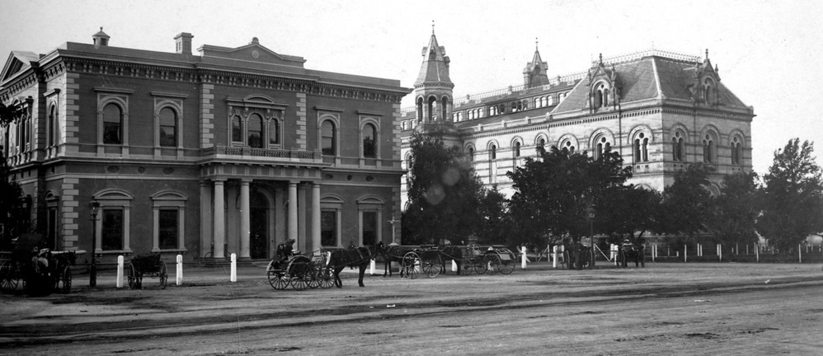 Image: view from street of two large ornate buildings with horse-drawn carts in the front