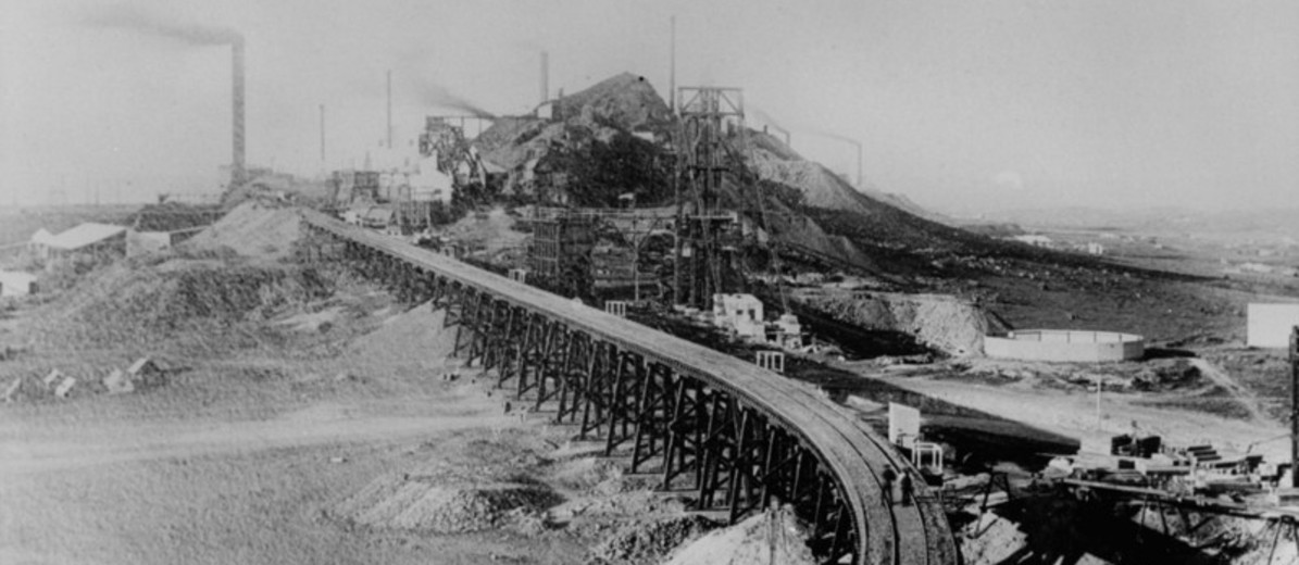 Image: railway tracks approaching slag heap with chimneys and large steel structures visible