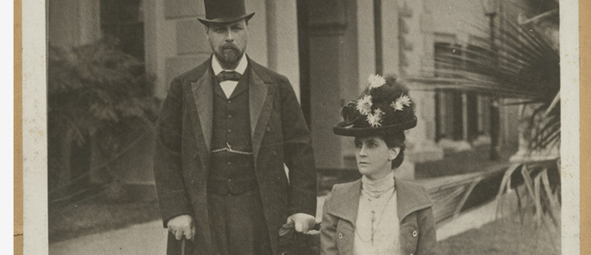 Image: Man in suit and top hat next to women sitting in dress and hat