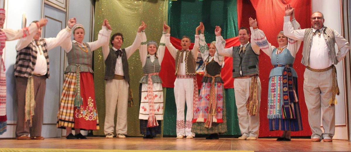 Group of people in costume on stage with large 100 