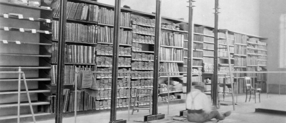 Image: shelves full of documents with person sitting on floor