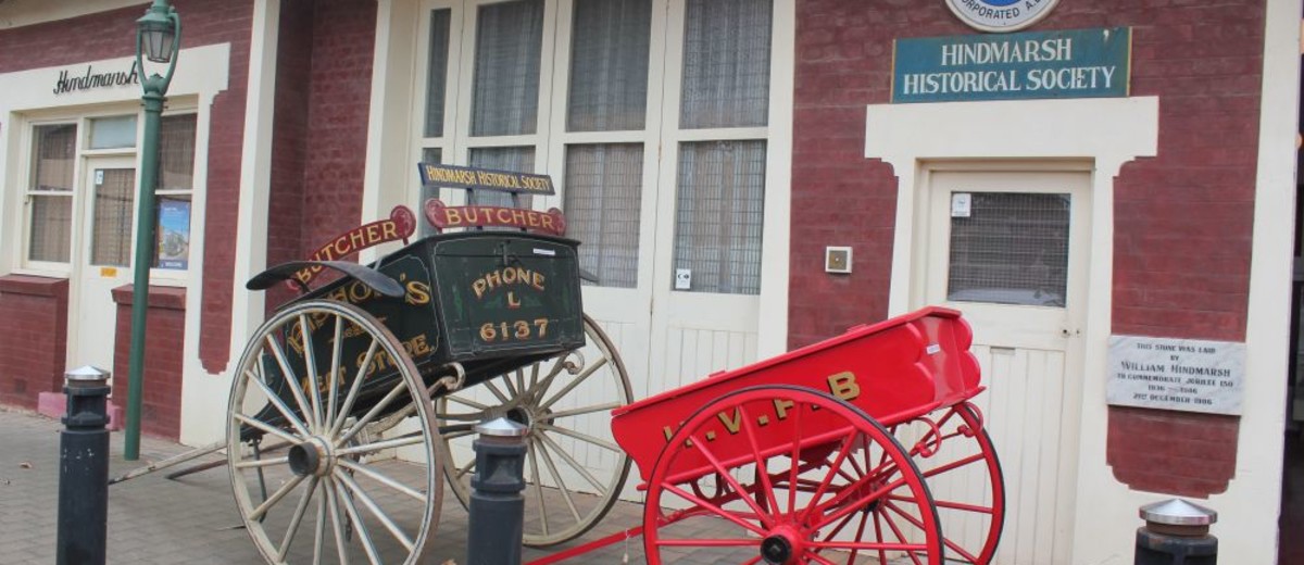 Image: Restored horse-drawn cart outside of a historical society building.
