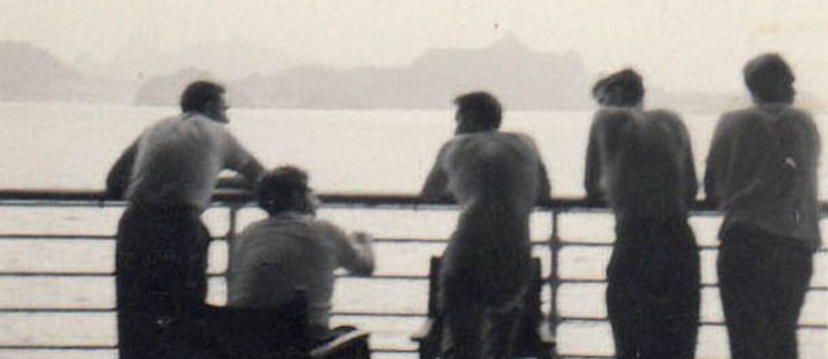 Image: silhouette of five men from behind, standing on board a ship