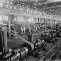 Image: A display of 1880s "electric light machinery" featuring wheels and belts in a large hall.