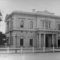 Image: Front of large, two-storey historic building with columns bordering its front door