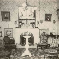 Image: Black and white photograph of interior of room, with floral-print furniture and wallpaper