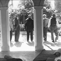 Image: Five Afghan men stand in the courtyard of a building. Two ornate columns are visible in the foreground