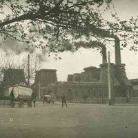 Image: A factory with two large chimneys spews black smoke.