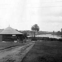 Image: a round kiosk building on the bank of a river.