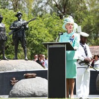 Image: woman at lectern speaking in front of sculpture