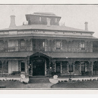 Image: large two story building with smaller third story and wrap around verandah