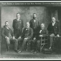 Image: black and white shot of six men, four are sitting and two are standing