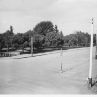 Image: One corner of a large park. A street with a lone gaslight lamp is visible in the foreground