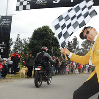 Image: man waving checkered flag as motorbike rides away