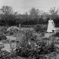Image: Two young women stand in a large garden with a variety of flowering and other plants