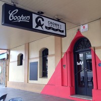 Image: beige building with red triangle over front door, with neon sign hanging above