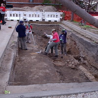 Image: large hole in the ground with people standing in the bottom and above
