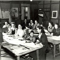 Image: man standing in front of group of women and children sitting at desks