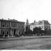 Image: view from street of two large ornate buildings with horse-drawn carts in the front