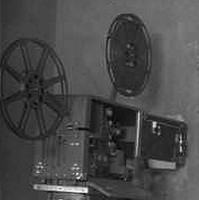 Image: Two film projectors of 1940s vintage stand in a projection room that is likely located within a cinema
