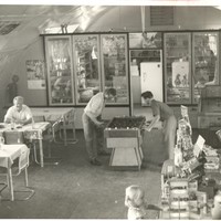 Image: interior of building with curved roof, people at game table