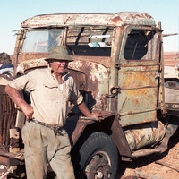Image: Man leans on rusted truck 