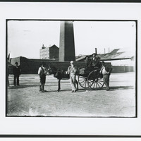 A group of men with cart standing outside the masonry perimeter wall of the copper smelter