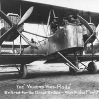 Image: bi-plane on ground with men in cockpit and standing on lower wing