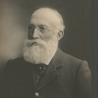 Image: A photographic portrait of an elderly man with a full, white beard and wire-rimmed glasses