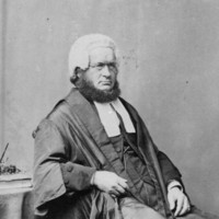 Image: Black and white portrait of a man, with the chin curtain beard popular at the time. He is seated and wearing his wig and gown.