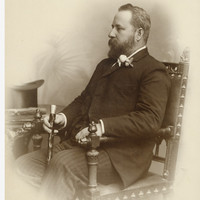 Image: caucasian man with beard holding a cane poses for photograph in chair