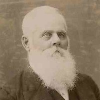Image: A photographic head-and-shoulders portrait of an elderly man dressed in late-nineteenth century attire and sporting a long white beard