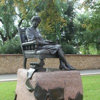 Image: bronze statue of seated woman with books