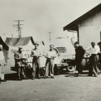 Image: group of men in front of tin huts