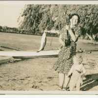 Image: Women holding fishing rod with fish next to small boy