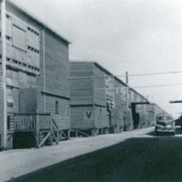 Image: row of tin buildings with car parked on dirt road
