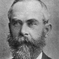 Image: A photographic portrait of a middle-aged man in late-Victoran attire with a salt-and-pepper beard and thinning hair
