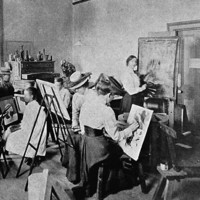 Image: A group of women in Edwardian attire paint at easels in a large, open room