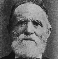 Image: A photographic head-and-shoulders portrait of an elderly Caucasian man with a white beard. He is wearing a late nineteenth century suit with bowtie