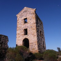 Image: Front view of a tall ruined building surrounded by small bushes