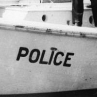 Image: A group of policemen stand on a small motor boat. One of the policemen is pointing and directing others to perform specific activities