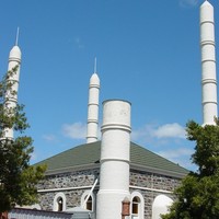 Image: A grey stone building bracketed by three minarets