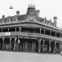Image: A large three storey corner hotel with a second floor balcony also forming a verandah and gable windows. 