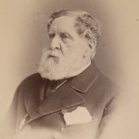 Image: a photographic head and shoulders portrait of an elderly bearded man in three-quarter profile. 