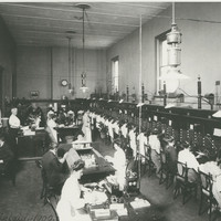 Image: A busy telephone exchange. There are rows of switchboard operators and several other staff supervising