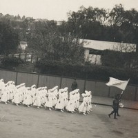 Image: group of women in white uniforms marching along the street