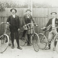 Image: three cyclists in hats pose with their bicycles